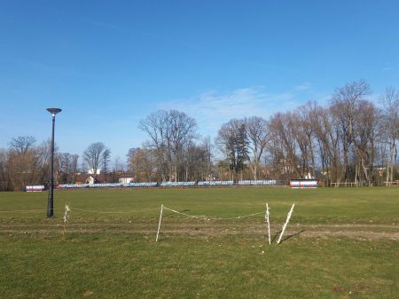 panorama stadionu piłkarskiego w Zabłudowie. Ławki rezerwowyach, krzesełka w kolorze niebieskim i czerwonym