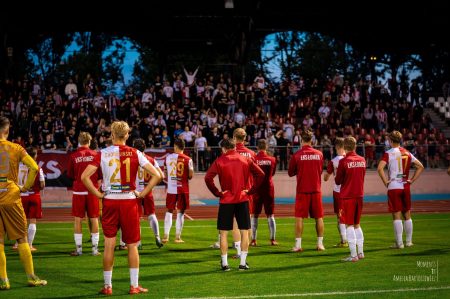 Piłkarze ŁKS-u Łomża stoją przodem do kibiców którzy są na trybunach